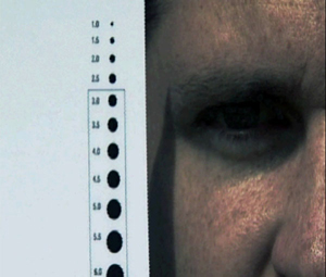 An image of a pupil measurement card held up to a man's face