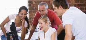 Photo of four people around a computer screen